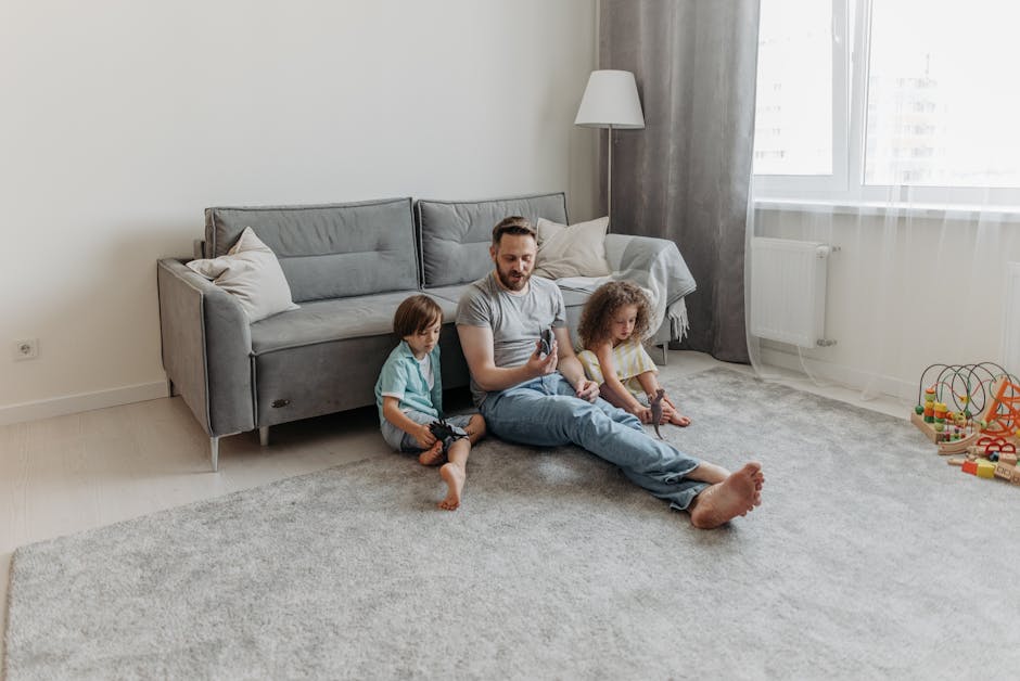 A spacious, sunlit living room with beige carpet flooring and soft yellow walls featuring white crown molding. The room has a curved wall with five large double-hung windows, each dressed with pink an
